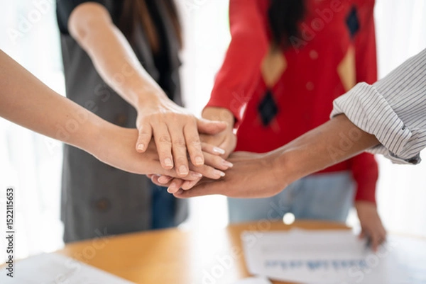 Fototapeta Team building group of people Asian business hands stack unity and support Team fold their hands on each other