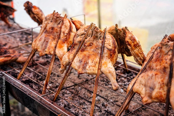 Fototapeta Kai Yang Wichian Buri Whole grilled chicken marinated in traditional spices on the charcoal stove on stalls are located on the roadside is very Popular Street food of Thailand.