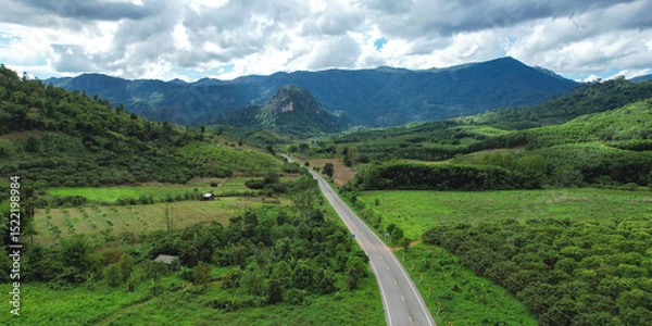 Fototapeta Aerial view of the road among the forest and mountains