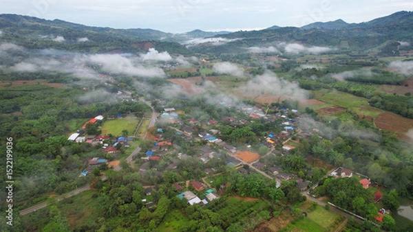 Fototapeta Aerial view from drone of the rural village in the mountains on foggy day