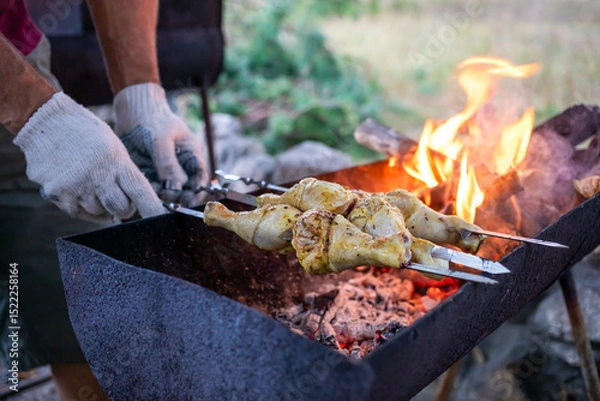 Obraz Grilling marinated chicken skewers over an open flame in a rustic outdoor setting