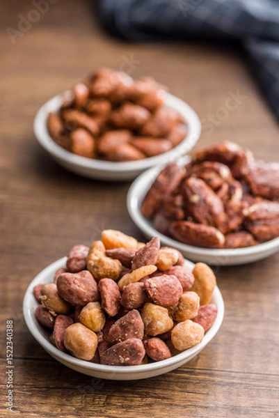 Fototapeta Nuts coated in sugar and honey in bowl on wooden table.