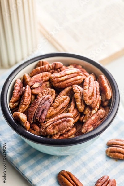 Fototapeta Peeled pecan nuts in bowl on white table.