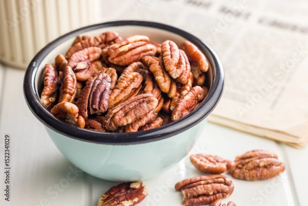Fototapeta Peeled pecan nuts in bowl on white table.