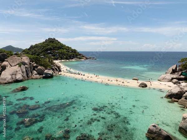 Fototapeta Sandbar connecting two areas surrounded by turquoise waters and tropical scenery under clear skies. Thailand, Koh Tao.