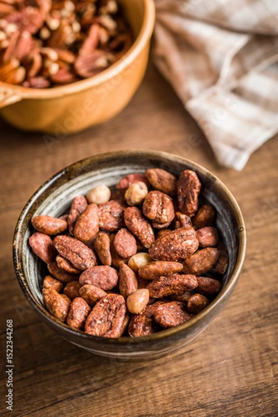 Fototapeta Nuts coated in sugar and honey in bowl on wooden table.