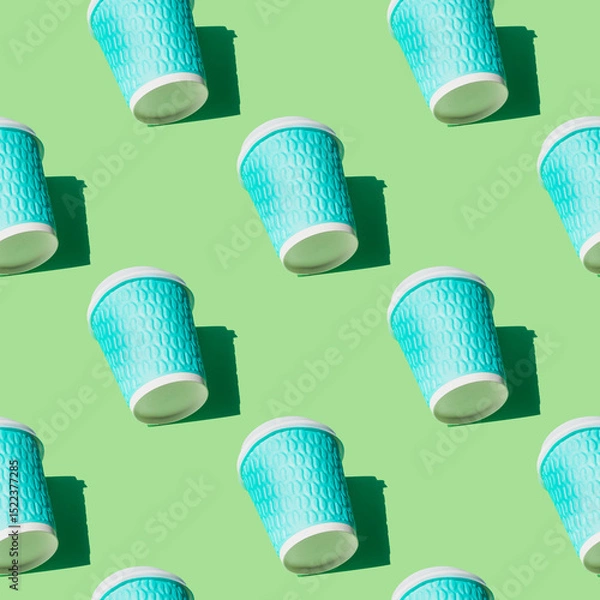 Fototapeta Coffee cup pattern on green background. Textured turquoise paper cups with white lids and natural bright sunny shadows. Hot drinks to go. Top view. Takeaway coffee