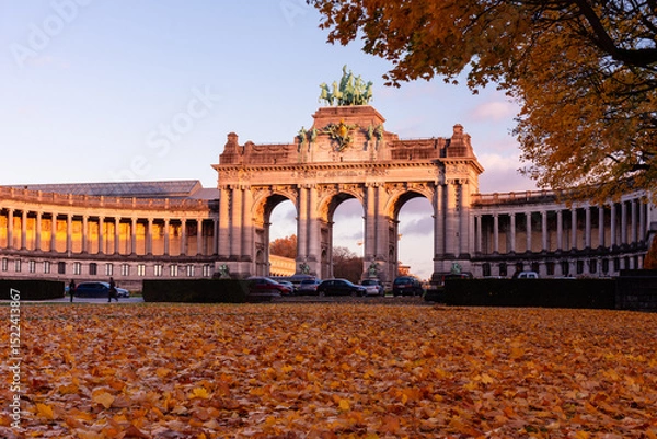 Fototapeta Low angle view of the Cinquantenaire Arcade at sunset in autumn, with fallen leaves covering the foreground