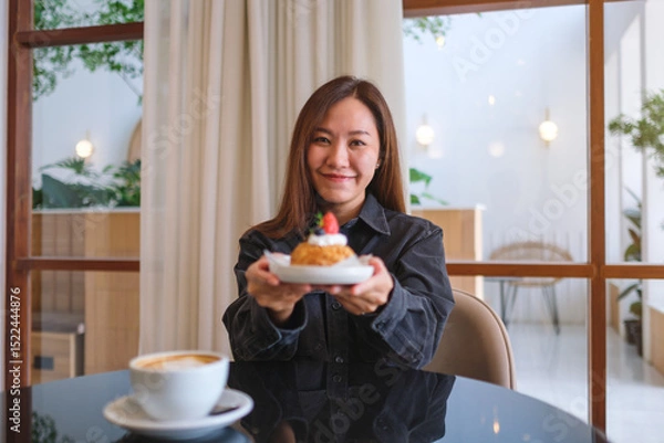 Fototapeta Portrait image of a woman holding and serving a plate of strawberry choux cream