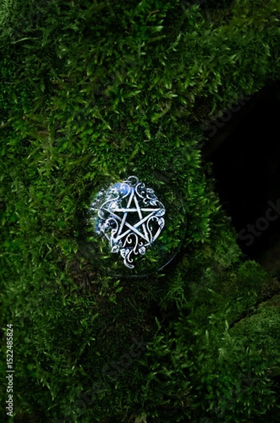 Fototapeta amulet with pentagram on green moss close up, abstract forest background. spiritual ritual. magic, witchcraft, pagan traditions, wiccan practice. esoteric symbol of pentacle. top view. copy space
