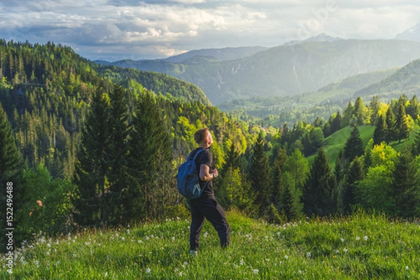 Fototapeta Man with backpack enjoying view of Slovenian Alps in Triglav National Park during scenic mountain hike