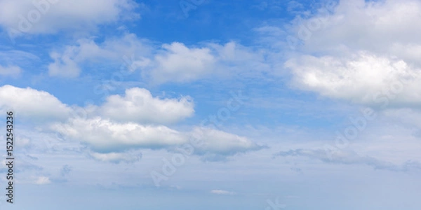 Obraz Light and fluffy white cumulus clouds scatter across a bright blue sky