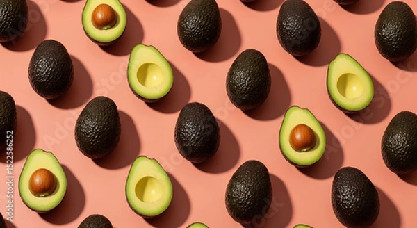 Fototapeta A repeating pattern of whole and halved avocados on a light pink background with soft shadows cast