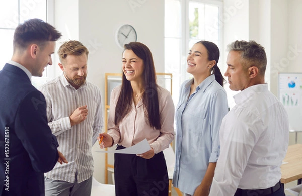 Fototapeta Team of office people conducting a group meeting, laughing and communicating. This business environment fosters teamwork, connection, and effective collaboration for achieving goals.