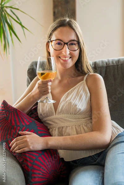 Obraz A smiling young woman drinking wine in available light