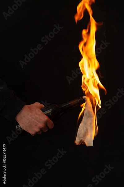 Obraz Close-up of burning bottle in hand on black background,