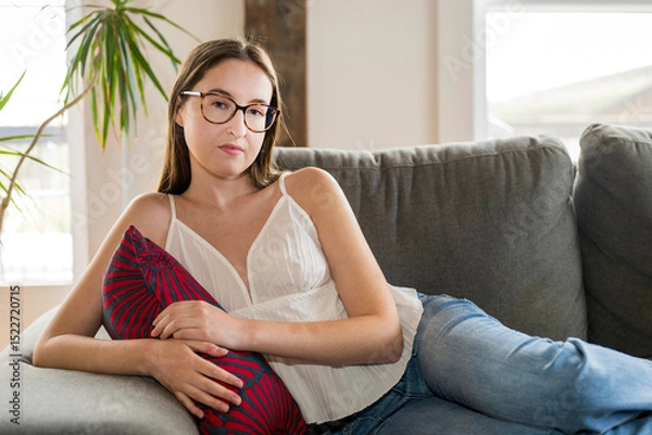 Obraz A portrait of a young girl wearing glasses sitting on a couch