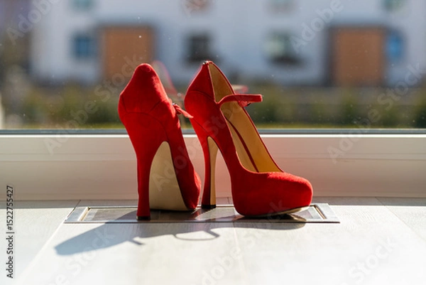 Fototapeta Red ladies pumps on the floor in front of a window