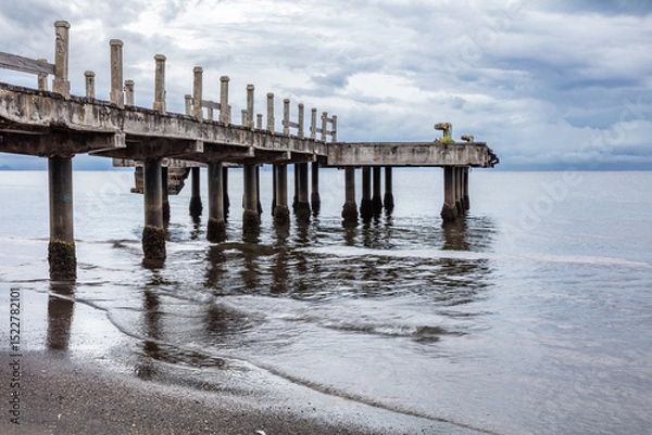 Obraz Pier in Lovina Beach, Northern Bali, Indonesia. Calm water; beach in foreground. Cloudy sky overhead. 
