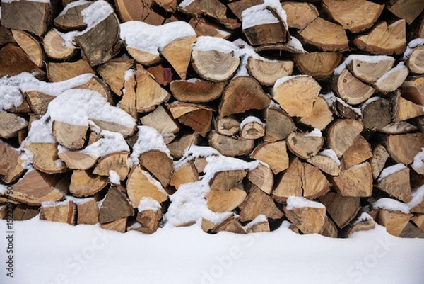 Fototapeta Zimowy widok na drewno opałowe starannie ułożone w drewnianej drewutni, częściowo przysypane świeżym śniegiem. Naturalne światło i spokojna, wiejska sceneria. Symbol przygotowań do zimy i życia na wsi