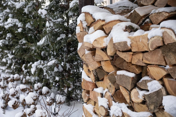 Fototapeta Zimowy widok na drewno opałowe starannie ułożone w drewnianej drewutni, częściowo przysypane świeżym śniegiem. Naturalne światło i spokojna, wiejska sceneria. Symbol przygotowań do zimy i życia na wsi