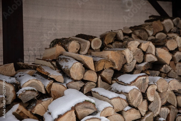 Fototapeta Zimowy widok na drewno opałowe starannie ułożone w drewnianej drewutni, częściowo przysypane świeżym śniegiem. Naturalne światło i spokojna, wiejska sceneria. Symbol przygotowań do zimy i życia na wsi