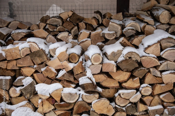 Fototapeta Zimowy widok na drewno opałowe starannie ułożone w drewnianej drewutni, częściowo przysypane świeżym śniegiem. Naturalne światło i spokojna, wiejska sceneria. Symbol przygotowań do zimy i życia na wsi