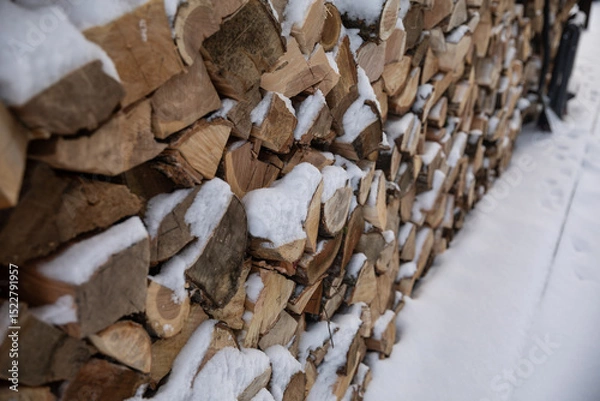 Fototapeta Zimowy widok na drewno opałowe starannie ułożone w drewnianej drewutni, częściowo przysypane świeżym śniegiem. Naturalne światło i spokojna, wiejska sceneria. Symbol przygotowań do zimy i życia na wsi