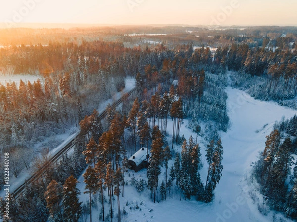Fototapeta A road  winds through a snowy forest, where frosty trees