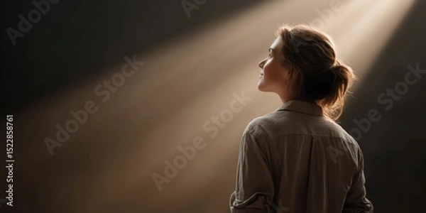 Obraz businesswoman career goal-setting. A woman in a dimly lit space, illuminated by soft beams of light.