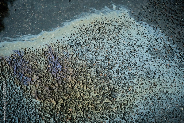 Fototapeta Colorful gasoline or oil spill creating a rainbow sheen reflecting on a wet asphalt road surface.
