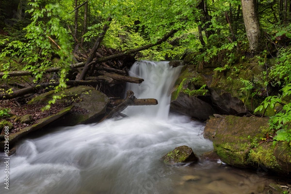 Obraz Waterfall in the mountains, river rapids, fast flow, Scenic view of pristine Carpathian nature with crystal clear water cascading over mossy rocks. Photo wallpaper, beauty of nature and the Earth.