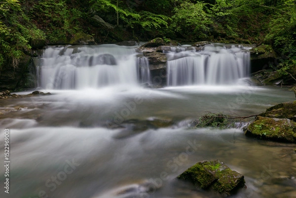 Obraz Waterfall in the mountains, river rapids, fast flow, Scenic view of pristine Carpathian nature with crystal clear water cascading over mossy rocks. Photo wallpaper, beauty of nature and the Earth.
