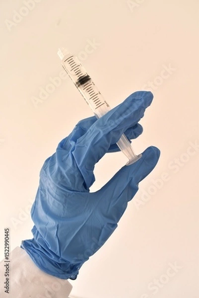 Fototapeta Syringe in gloved hands of a doctor. Medical procedure preparation, symbolizing care, precision, and hygiene.

