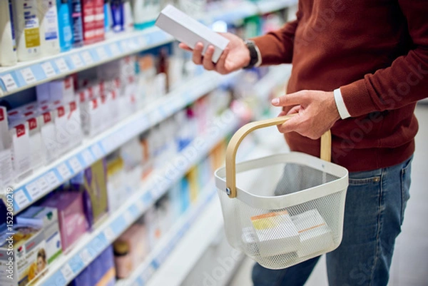 Fototapeta Person Shopping in Pharmacy Aisle Holding a Basket and Inspecting Products