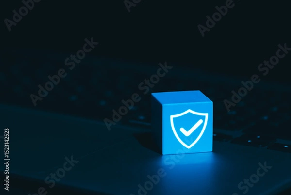 Obraz Cybersecurity and Data Protection Symbol Concept. A glowing blue cube with shield and checkmark icon on laptop keyboard, symbolizing cyber security, digital protection, trusted data security systems,