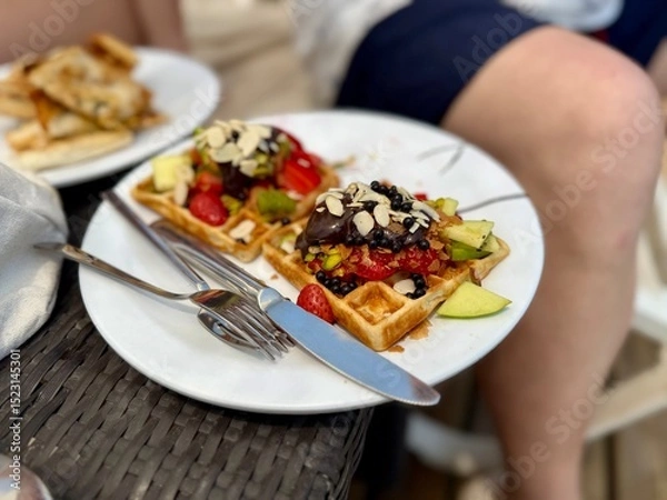 Fototapeta Delicious homemade waffles with whipped cream and fresh fruit. Served on a paper tray or plate. Home production plant.