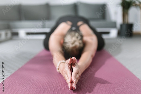 Obraz Yoga practitioner stretching on mat in a calming indoor space during a wellness routine
