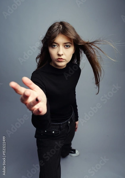 Fototapeta  Intense Young Woman Reaching Towards Camera with Blowing Hair
