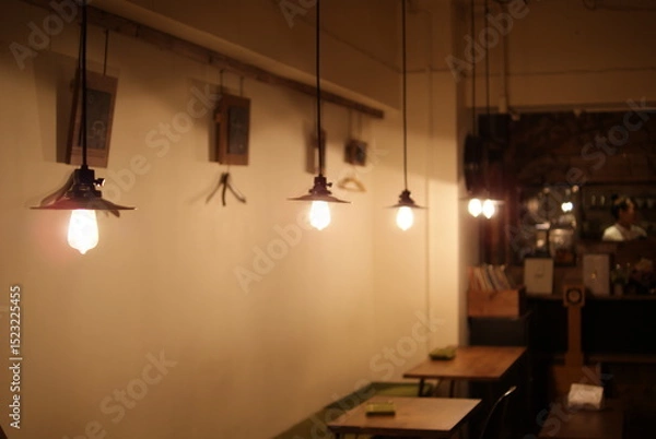Obraz 工業系デザインのペンダントライトが連なるカフェの温かな空間


