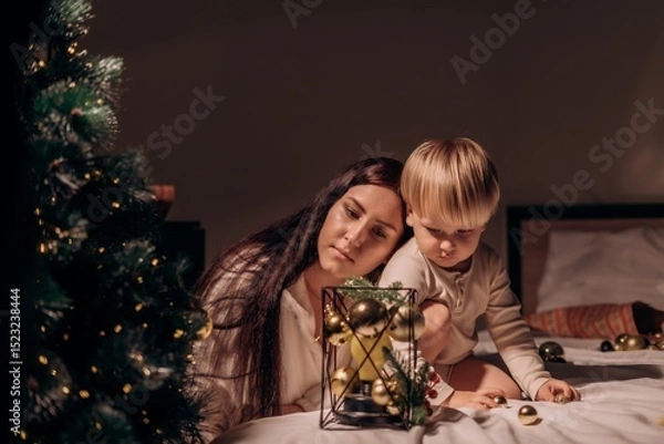 Fototapeta Mother and son rest their heads together watching Christmas decor in peaceful shared stillness full of warmth intimacy and quiet attention to gentle holiday moments