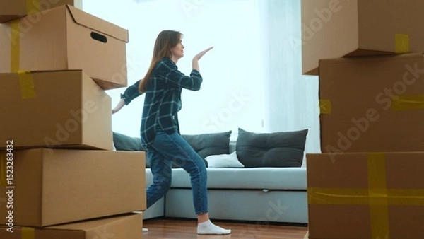 Fototapeta Happy positive couple of man and woman having fun dancing in room in new home with many boxes. Caucasian young wife and husband doing funny dance in new apartment. Moving in together