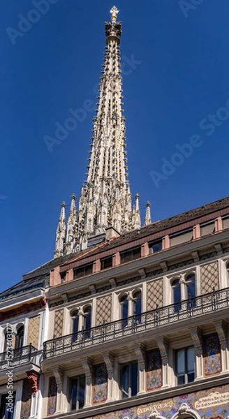 Obraz Vienna, Austria - 05 19 2024: The main spire of St Stephens Cathedral rises behind a beautiful building facade in the center of Vienna.