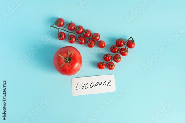 Fototapeta Red tomatoes and cherry tomatoes in close-up on a pink background the inscription lycopene as the main antioxidant in tomatoes