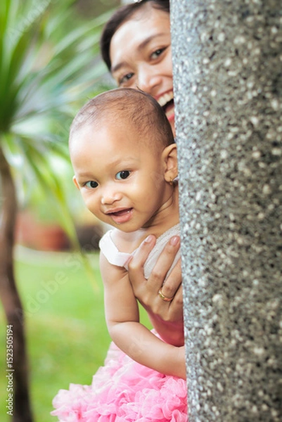 Fototapeta Asian mother and toddler girl happy playing peek a boo  or hide and seek together