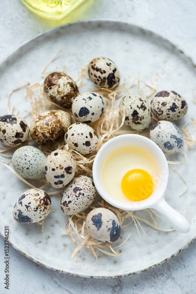 Fototapeta White plate with fresh uncooked quail eggs, vertical shot, middle closeup, selective focus