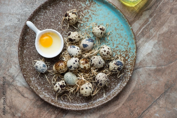 Fototapeta Brown plate with raw fresh quail eggs, horizontal shot on a brown granite background, view from above