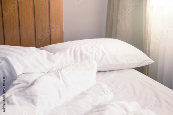 Obraz white pillow and blanket with wrinkle messy on bed in bedroom with lighting upper left side, from sleeping in a long night winter.