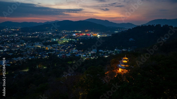 Obraz Aerial view of scenery Khao Rang viewpoint at twilight.
view of a town nestled among lush green mountains at sunset, with a Pavilion structure perched on the hillside at Phuket town at Dusk