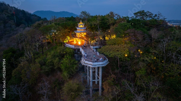 Obraz Aerial view of scenery Khao Rang viewpoint at twilight.
view of a town nestled among lush green mountains at sunset, with a Pavilion structure perched on the hillside at Phuket town at Dusk